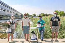Dr. Silke Göttler of the Biogents AG (Regensburg) and members of HNU’s DigiHealth Institute with a "BG-Trap Station" including an electronic mosquito counting module (in front) and two mobile BG-Pro traps at the HNU lake.